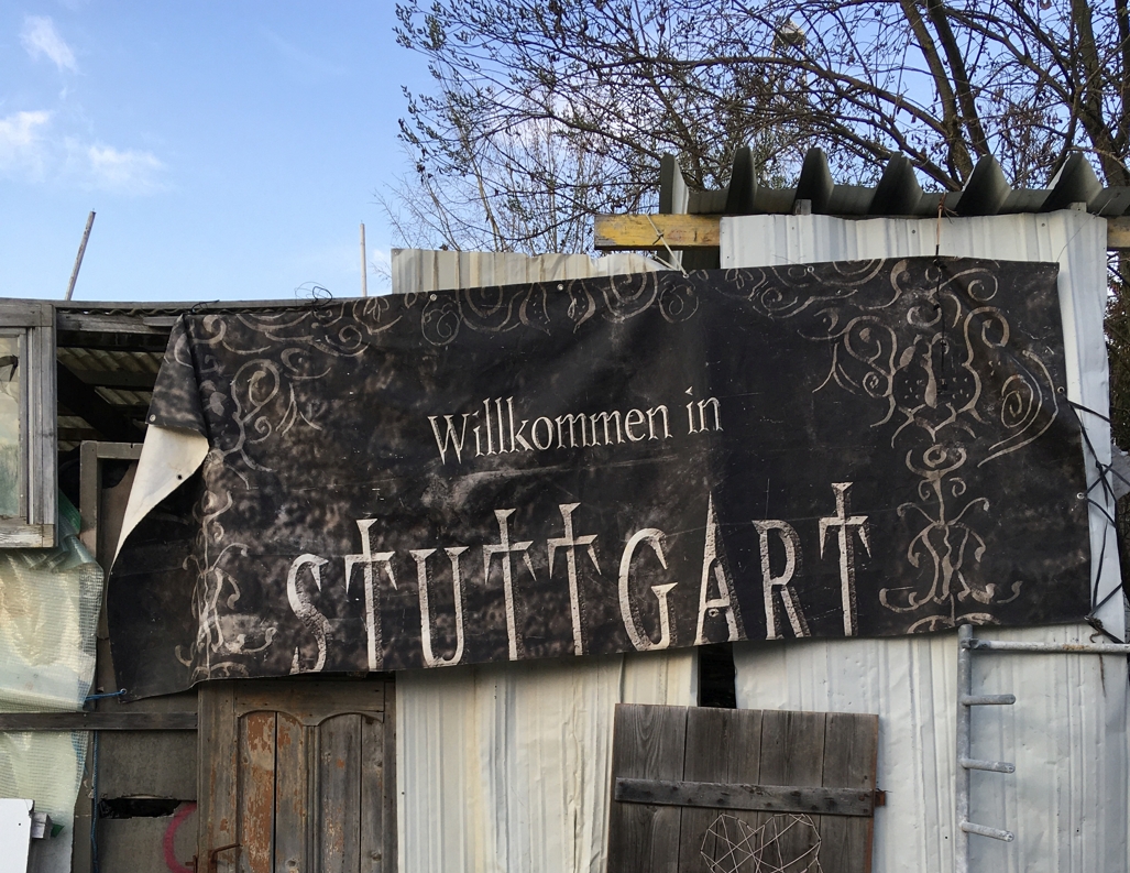 Ein Spruchband "Willkomen in Stuttgart" vor einer Bretterbude